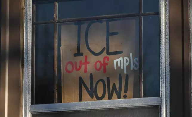 A sign is posted on a residential window near the scene of the fatal shooting involving federal law enforcement agents, Wednesday, Jan. 7, 2026, in Minneapolis. (AP Photo/Tom Baker)