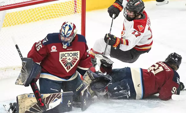 Ottawa Charge's Gabbie Hughes (17) is upended by Montreal Victoire's Maggie Flaherty (91) as she moves in on Victoire goaltender Ann-Renee Desbiens (35) during the second period of an PWHL hockey game in Laval, Que., Saturday, Jan. 24, 2026. (Graham Hughes/The Canadian Press via AP)
