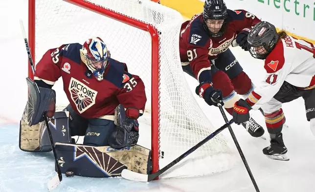 Ottawa Charge's Brooke Hobson (11) attempts a wraparound on Montreal Victoire goaltender Ann-Renee Desbiens (35) as Victoire's Maggie Flaherty (91) defends during third period PWHL hockey action in Laval, Quebec, Canada, Saturday, Jan. 24, 2026. (Graham Hughes/The Canadian Press via AP)