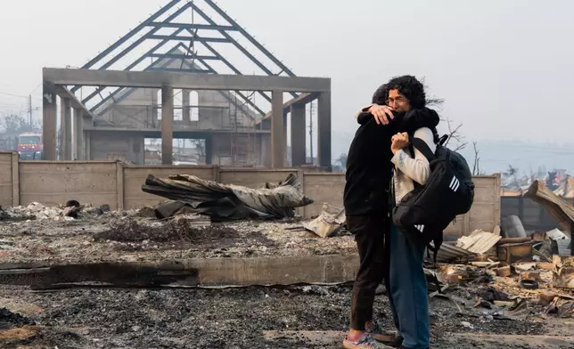 Mirtza Aguilera, right, and her daughter embrace in front of their home burned by wildfires in Tome, Chile, Monday, Jan. 19, 2026. (AP Photo/Javier Torres)