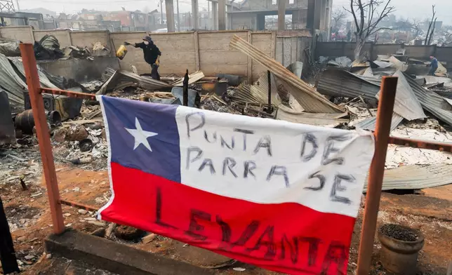 A Chilean flag is covered by the Spanish message: "Punta Arenas rises" at a home destroyed by wildfires in Tome, Chile, Monday, Jan. 19, 2026. (AP Photo/Javier Torres)