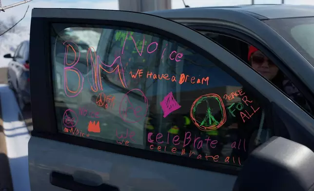 A protester writes pro BLM and Anti-ICE rhetoric on the window of her car during an ICE protest and celebration of MLK day, Monday, Jan. 19, 2026 in St. Paul, Minn. (AP Photo/Angelina Katsanis)