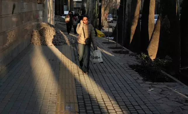 People walk along the sidewalk in northern Tehran, Iran, Tuesday, Jan. 27, 2026. (AP Photo/Vahid Salemi)