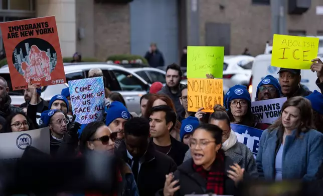 People raise signs during a news conference outside Greater New York Federal Building, Tuesday, Jan. 13, 2026, in New York. (AP Photo/Yuki Iwamura)