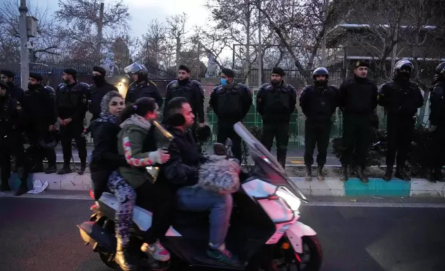Policemen protect the British Embassy during a protest by hardline supporters of the Iranian government, as people ride on their motorbike in Tehran, Iran, Wednesday, Jan. 14, 2026. (AP Photo/Vahid Salemi)