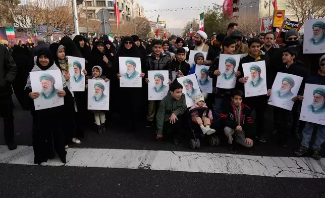 People hold posters of the Iranian Supreme Leader Ayatollah Ali Khamenei during a funeral ceremony for a group of security forces, who were killed during anti-government protests, in Tehran, Iran, Wednesday, Jan. 14, 2026. (AP Photo/Vahid Salemi)