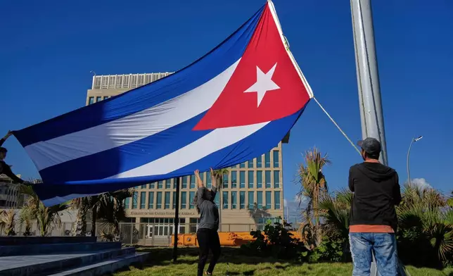 Workers fly the Cuban flag at half-mast at the Anti-Imperialist Tribune near the U.S. embassy in Havana, Cuba, Monday, Jan. 5, 2026, in memory of Cubans who died two days before in Caracas, Venezuela during the capture of Venezuelan President Nicolas Maduro by U.S. forces. (AP Photo/Ramon Espinosa)