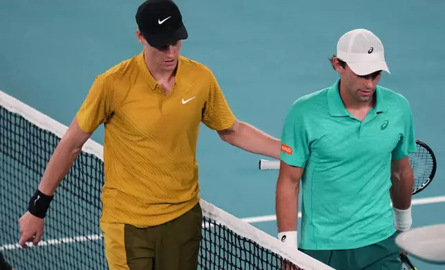 Jannik Sinner, left, of Italy walks from the court with Eliot Spizzirri of the U.S. after winning their third round match at the Australian Open tennis championship in Melbourne, Australia, Saturday, Jan. 24, 2026. (AP Photo/Dar Yasin)
