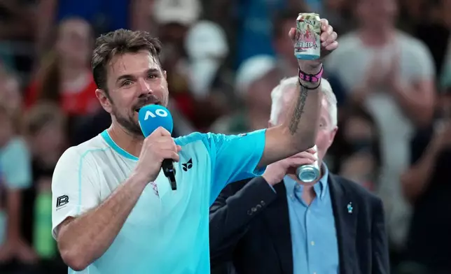 Stan Wawrinka of Switzerland holds up a beer following his third round loss to Taylor Fritz of the U.S. at the Australian Open tennis championship in Melbourne, Australia, Saturday, Jan. 24, 2026. (AP Photo/Asanka Brendon Ratnayake)