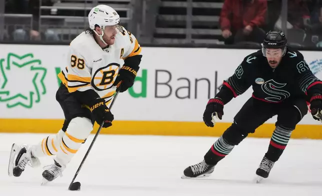 Boston Bruins right wing David Pastrnak moves the puck against Seattle Kraken center Frederick Gaudreau, right, during the third period of an NHL hockey game Tuesday, Jan. 6, 2026, in Seattle. (AP Photo/Lindsey Wasson)