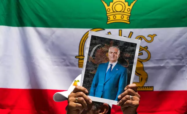 A protester holds a poster of Iran's exiled crown prince Reza Pahlavi during a rally in support of anti-government protests in Iran, outside Iran's embassy in Santiago, Chile, Tuesday, Jan. 13, 2026. (AP Photo/Esteban Felix)