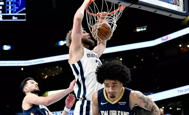 Memphis Grizzlies center Jock Landale (31) dunks over New Orleans Pelicans forward Karlo Matkovic, left, and guard Micah Peavy, right, in the first half of an NBA basketball game Friday, Jan. 23, 2026, in Memphis, Tenn. (AP Photo/Brandon Dill)