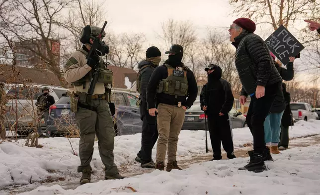 EDS NOTE: OBSCENITY - A woman yells at federal immigration officers as they make an arrest Sunday, Jan. 11, 2026, in Minneapolis. (AP Photo/John Locher)