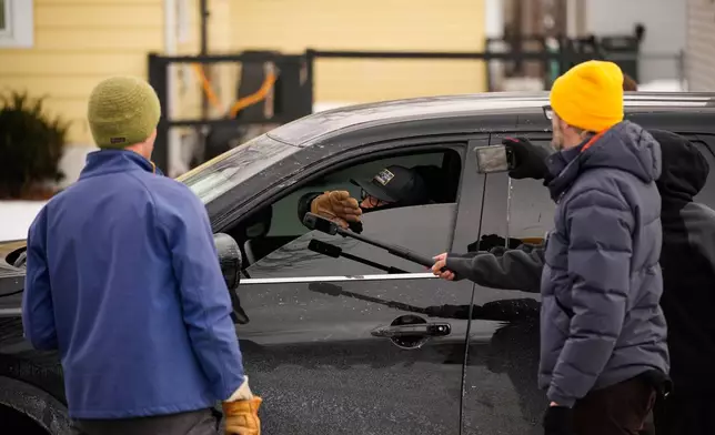 Bystanders film a federal immigration officer in their car Sunday, Jan. 11, 2026, in Minneapolis. (AP Photo/John Locher)
