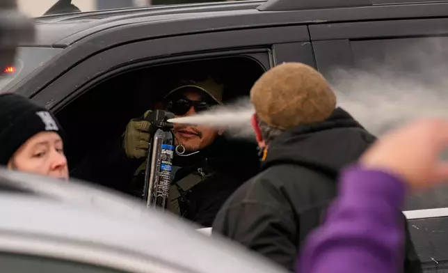 A federal immigration officer deploys pepper spray as officers make an arrest Sunday, Jan. 11, 2026, in Minneapolis. (AP Photo/John Locher)
