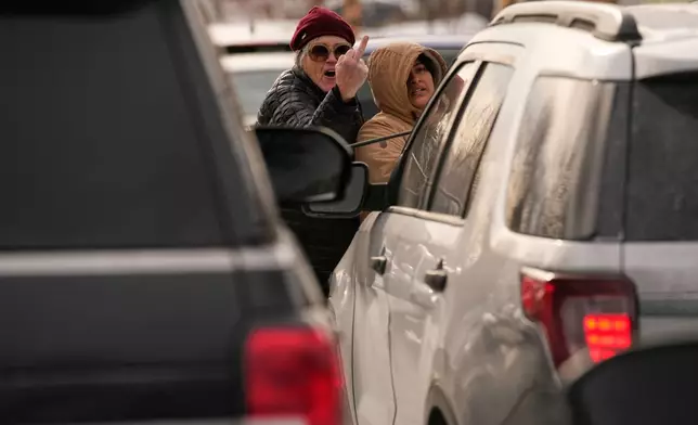 EDS NOTE: OBSCENITY - A woman gestures at federal immigration officers as they make an arrest Sunday, Jan. 11, 2026, in Minneapolis. (AP Photo/John Locher)