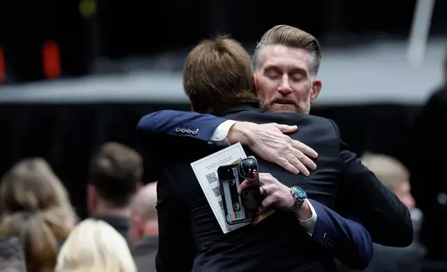 ESPN's Marty Smith, right, hugs a person at the NASCAR Plane Crash Memorial memorial in Charlotte, N.C., Friday, Jan. 16, 2026. (AP Photo/Nell Redmond)
