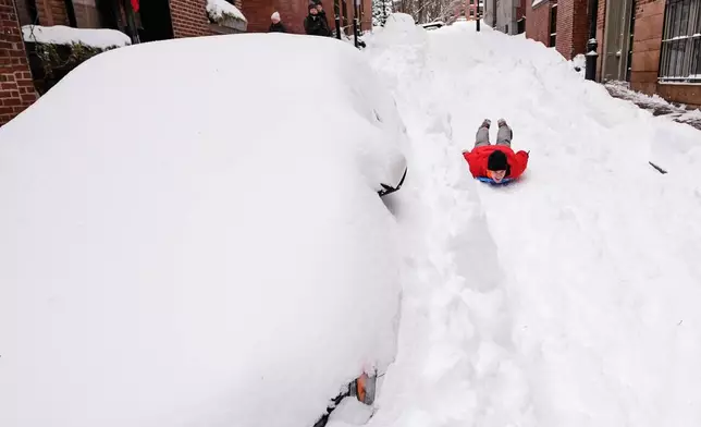 Ian Flood sleds down a street in his Beacon Hill neighborhood following a winter storm that dump more than a foot of snow across the region, Monday, Jan. 26, 2026, in Boston. (AP Photo/Charles Krupa)
