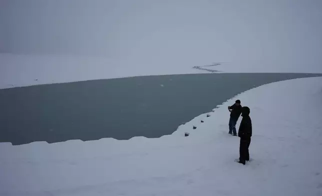People take photos at Lake Michigan in Chicago, Sunday, Jan. 25, 2026. (AP Photo/Nam Y. Huh)