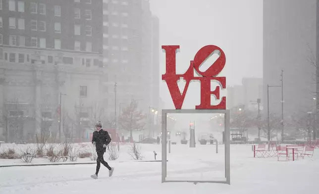 A person jogs at JFK Plaza, also knows as Love Park during a winter storm in Philadelphia, Sunday, Jan. 25, 2026. (AP Photo/Matt Rourke)