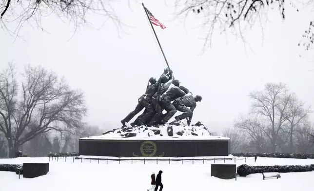 People walk past the Marine Corps War Memorial as snow falls, Sunday, Jan. 25, 2026, in Arlington, Va. (AP Photo/Julia Demaree Nikhinson)