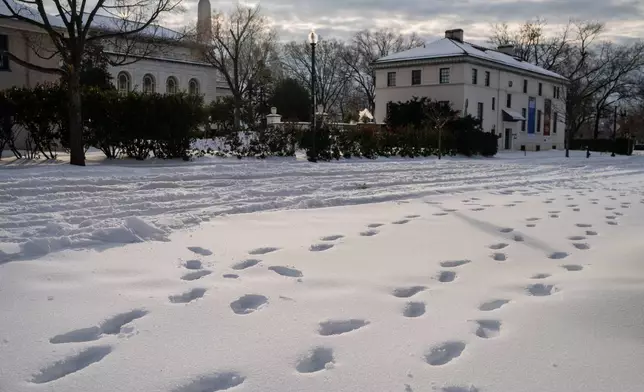 Footprints mark the snow in Washington, Monday, Jan. 26, 2026. (AP Photo/Allison Robbert)