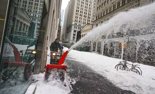 A worker uses a snow blower on Wall Street, in New York, Monday, Jan. 26, 2026. (AP Photo/Richard Drew)