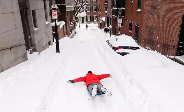 Ian Flood sleds down a street in his Beacon Hill neighborhood following a winter storm that dump more than a foot of snow across the region, Monday, Jan. 26, 2026, in Boston. (AP Photo/Charles Krupa)