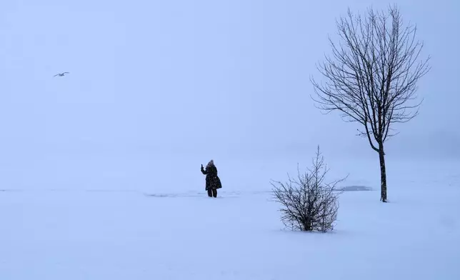 A person takes photos at Montrose beach in Chicago, Sunday, Jan. 25, 2026. (AP Photo/Nam Y. Huh)