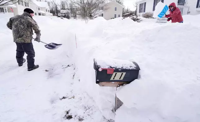 Todd Thibaud, left, and his wife Susan dig out their driveway and walkway following a winter storm that dumped more than a foot and a half of snow across the region, Tuesday, Jan. 27, 2026, in Haverhill, Mass. (AP Photo/Charles Krupa)