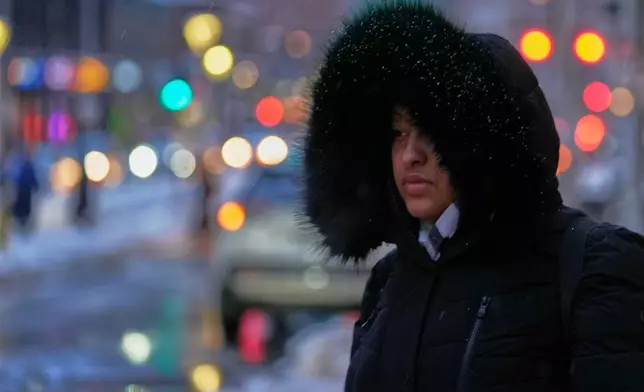 A pedestrian is bundled up against the frigid weather as she waits to cross an icy street, Monday, Jan. 26, 2026, in Boston. (AP Photo/Robert F. Bukaty)