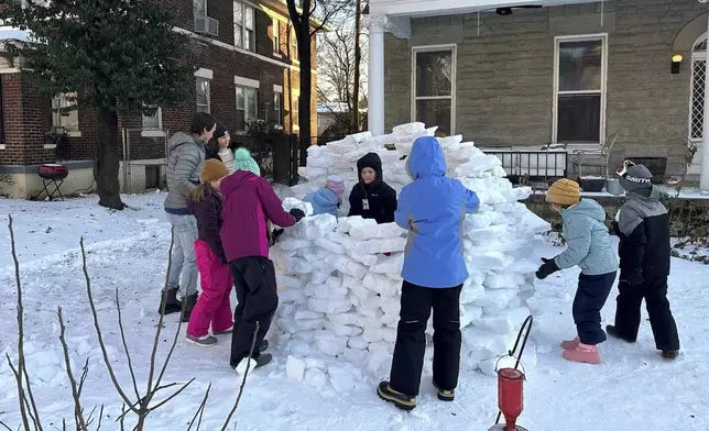 A group of children and adults build an igloo in the front yard of a home on Monday, Jan. 26, 2026, in Memphis, Tenn. (AP Photo/Adrian Sainz)