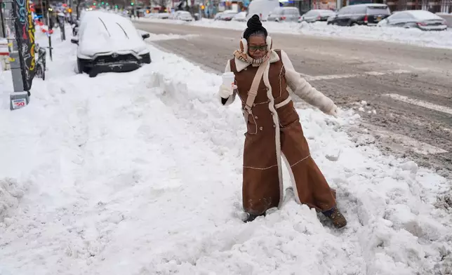 Carrie Hampton tries to navigate a snowy intersection without spilling her coffee in New York, Monday, Jan. 26, 2026. (AP Photo/Seth Wenig)