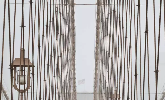 People walk across the Brooklyn Bridge during a winter storm, Sunday, Jan. 25, 2026, in New York. (AP Photo/Sydney Schaefer)