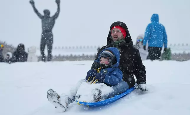 People sled at Philadelphia Art Museum steps by the Rocky statue during a winter storm in Philadelphia, Sunday, Jan. 25, 2026. (AP Photo/Matt Rourke)