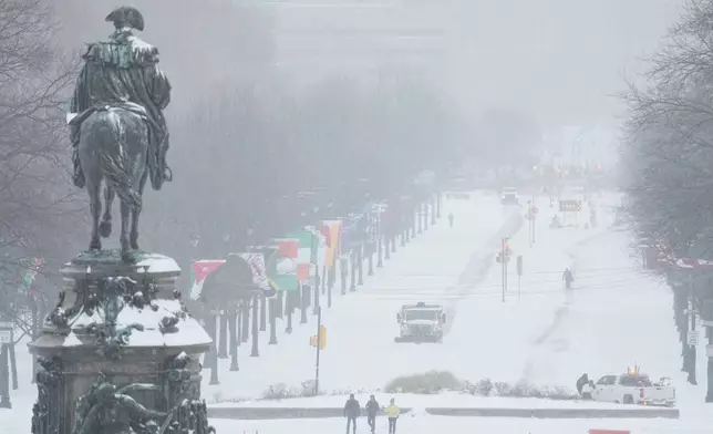 A plow removes snow on Benjamin Franklin Parkway as a statue of George Washington is seen at left during a winter storm in Philadelphia, Sunday, Jan. 25, 2026. (AP Photo/Matt Rourke)