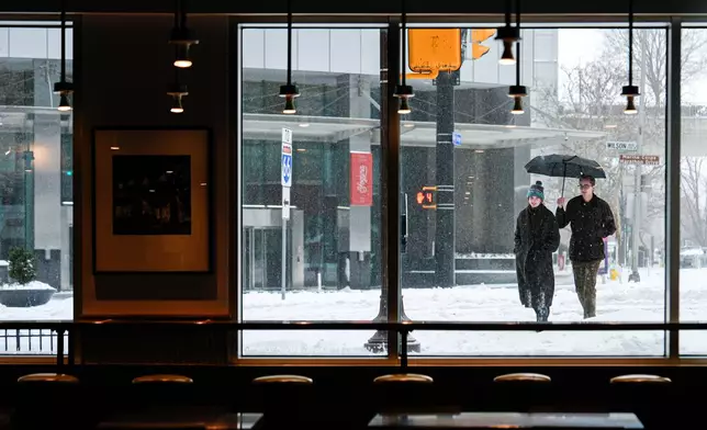 People walk through Arlington, Va. during a snowstorm, Sunday, Jan. 25, 2026. (AP Photo/Julia Demaree Nikhinson)