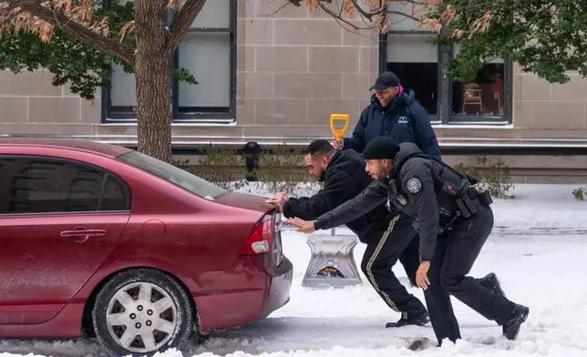 Secret Service officers help a car get out of a build-up of snow, Monday, Jan. 26, 2026, in Washington. (AP Photo/Allison Robbert)