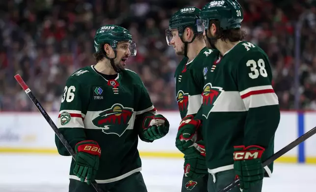 Minnesota Wild right wing Mats Zuccarello, left, talks with right wing Vladimir Tarasenko and right wing Ryan Hartman before a face-off against the Detroit Red Wings during the third period of an NHL hockey game Thursday, Jan. 22, 2026, in St. Paul, Minn. (AP Photo/Matt Krohn)