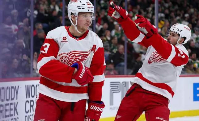 Detroit Red Wings left wing Lucas Raymond (23) celebrates after his goal as center Dylan Larkin, right, points to fans during the second period of an NHL hockey game against the Minnesota Wild, Thursday, Jan. 22, 2026, in St. Paul, Minn. (AP Photo/Matt Krohn)