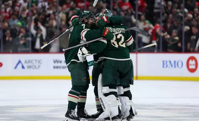 Minnesota Wild defenseman Brock Faber, goaltender Filip Gustavsson and center Vinnie Hinostroza celebrate their overtime win against the Detroit Red Wings after an NHL hockey game Thursday, Jan. 22, 2026, in St. Paul, Minn. (AP Photo/Matt Krohn)