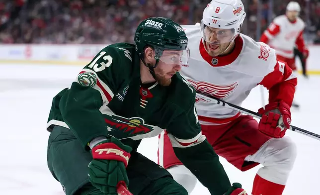 Minnesota Wild center Yakov Trenin, left, skates with the puck as Detroit Red Wings defenseman Ben Chiarot (8) defends during the third period of an NHL hockey game Thursday, Jan. 22, 2026, in St. Paul, Minn. (AP Photo/Matt Krohn)