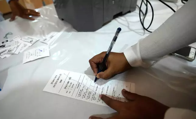 An official of the Union Election Commission checks a sample slip from an electronic voting machine as they prepare to set up a polling station opened at a monastery one day before the second phase of the general election in Yangon, Myanmar, Saturday, Jan. 10, 2026. (AP Photo/Thein Zaw)