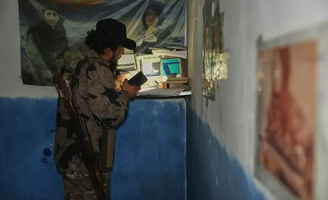 A Syrian security force member looks through documents inside a tunnel used by retreating Syrian Democratic Forces (SDF) fighters beneath Ain Issa, northeastern Syria, Saturday, Jan. 24, 2026. (AP Photo/Ghaith Alsayed)