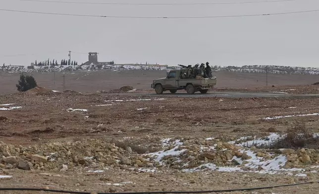 Syrian security force members ride in the back of a pickup truck in the town of Ain Issa, northeastern Syria, Saturday, Jan. 24, 2026. (AP Photo/Ghaith Alsayed)