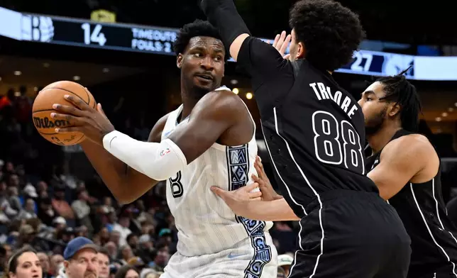Memphis Grizzlies forward Jaren Jackson Jr. (8) handles the ball against Brooklyn Nets guards Nolan Traore (88) and Cam Thomas, right, in the first half of an NBA basketball game, Sunday, Jan. 11, 2026, in Memphis, Tenn. (AP Photo/Brandon Dill)