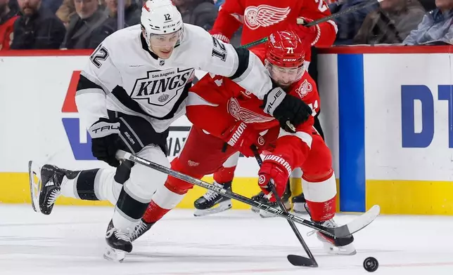 Los Angeles Kings left wing Trevor Moore (12) and Detroit Red Wings center Dylan Larkin (71) chase a loose puck during the second period of an NHL hockey game Tuesday, Jan. 27, 2026, in Detroit. (AP Photo/Duane Burleson)