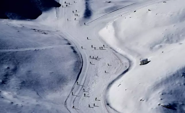 Skiers cast long shadows as they glide down a slope at the Mzaar-Kfardebian ski resort northeast of Beirut, Lebanon, Saturday, Jan. 3, 2026. (AP Photo/Hassan Ammar)