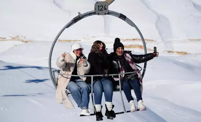 Tourists take selfies as they ride a chairlift at the Mzaar-Kfardebian ski resort northeast of Beirut, Lebanon, Saturday, Jan. 3, 2026. (AP Photo/Hassan Ammar)