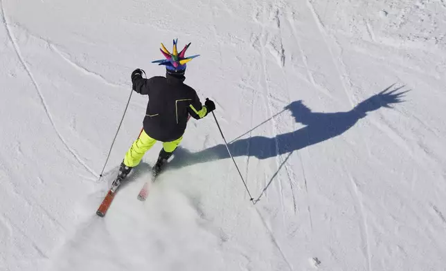 A skier wearing a colorful costume hat makes his way down a slope at the Mzaar-Kfardebian ski resort northeast of Beirut, Lebanon, Saturday, Jan. 3, 2026. (AP Photo/Hassan Ammar)